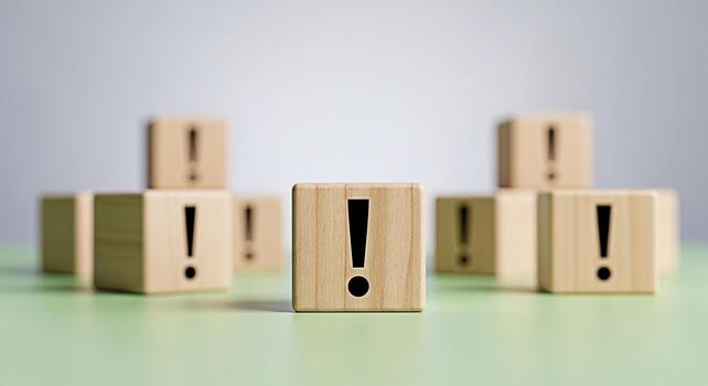 Wooden blocks displaying exclamation points on a green surface symbolizing urgency and attention to detail in a minimalist and clean studio setting conveying a sense of importance and caution photo
