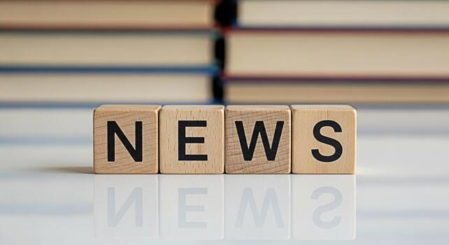 Wooden blocks spelling NEWS on a reflective surface with books in the background conveying information and current events in a simple and educational setting ideal for media and learning concepts photo