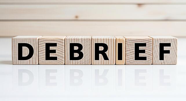 Wooden blocks spelling DEBRIEF on a reflective white surface against a light wood background symbolizing a postevent analysis and review process promoting learning and improvement in a clear and conci photo