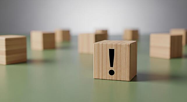 Wooden block displaying an exclamation mark on a green surface surrounded by other blocks creating a sense of urgency and importance in a minimalist and clean environment emphasizing attention to deta photo