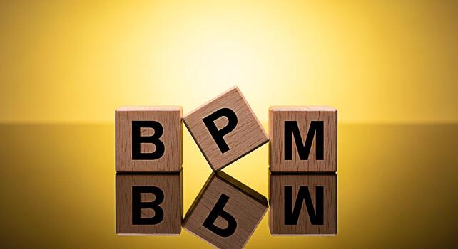 Conceptual BPM wooden blocks arranged on a reflective surface against a golden background representing business process management and optimization for efficiency and strategic planning in a modern bu photo
