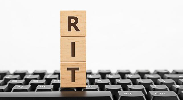 Wooden blocks spelling RIT resting on a black computer keyboard against a white background symbolizing technology education and the Rochester Institute of Technology with a clean and modern aesthetic photo