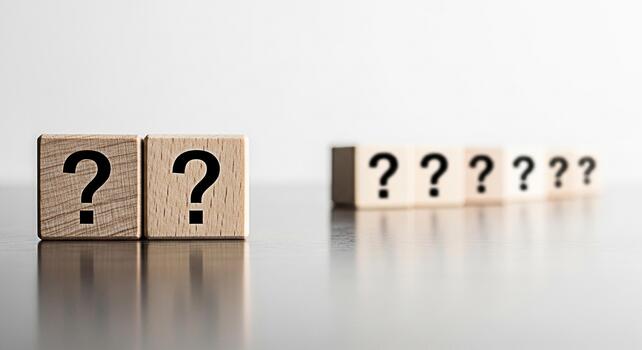 Wooden blocks displaying question marks on a reflective surface symbolizing uncertainty and the search for answers in a clean minimalist setting evoking curiosity and problemsolving photo