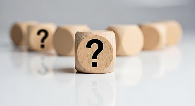 Wooden dice displaying a question mark on a white reflective surface representing uncertainty and the need for answers in a clean minimalist setting evoking curiosity and problemsolving photo