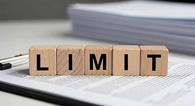 Wooden blocks spelling LIMIT resting on a document on a bright desk representing boundaries and restrictions in business and personal life promoting a sense of control and awareness photo