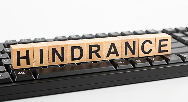 Wooden blocks spelling HINDRANCE resting on a black computer keyboard symbolizing obstacles and challenges in technology and business creating a mood of frustration and problemsolving photo