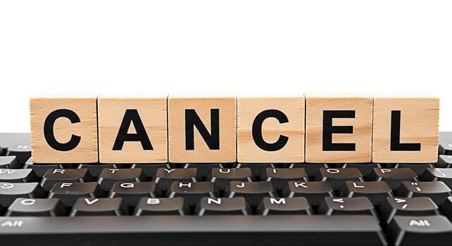 Wooden blocks spelling CANCEL sitting atop a black computer keyboard symbolizing termination cancellation or the end of a process in a digital environment conveying a sense of finality and decision photo