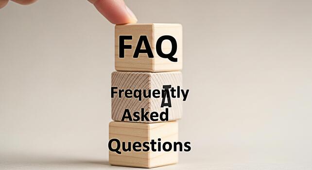 Hand placing a wooden block with FAQ on top of other blocks with Frequently Asked Questions in a bright studio setting representing information help and customer support photo