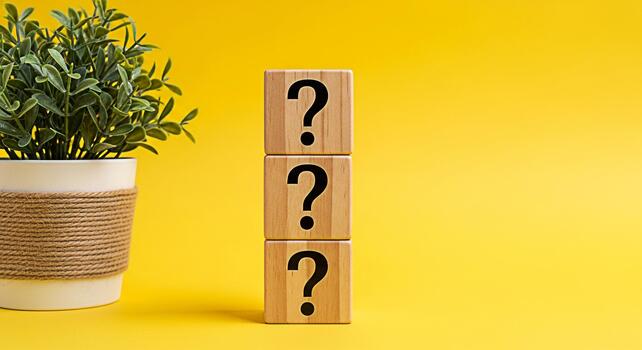 Stacked wooden blocks displaying question marks next to a potted plant on a bright yellow background symbolizing curiosity uncertainty and the search for answers in a vibrant and engaging setting photo