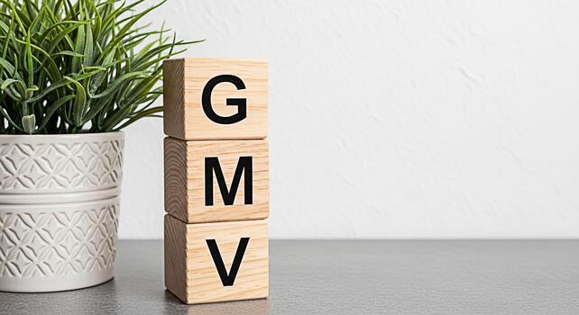 Wooden blocks displaying GMV next to a potted plant on a gray surface symbolizing growth marketing and value in a clean modern setting representing business success and positive financial performance photo