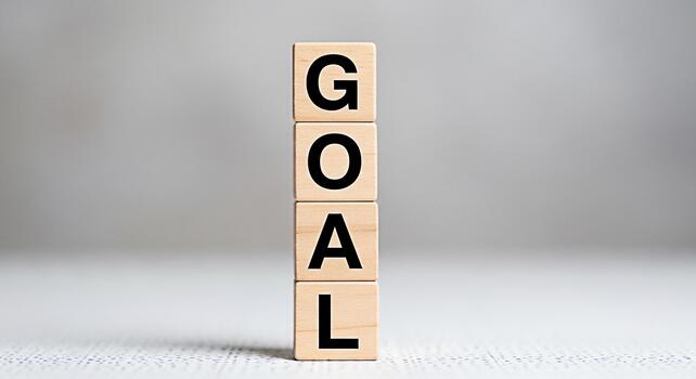 Wooden blocks spelling GOAL stacked in a bright studio setting symbolizing ambition and achievement representing the concept of setting targets and striving for success in business and personal life photo