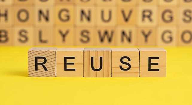 Wooden blocks spelling REUSE on a bright yellow surface promoting environmental awareness and sustainable practices in a simple impactful way emphasizing reduce reuse recycle for a greener future photo