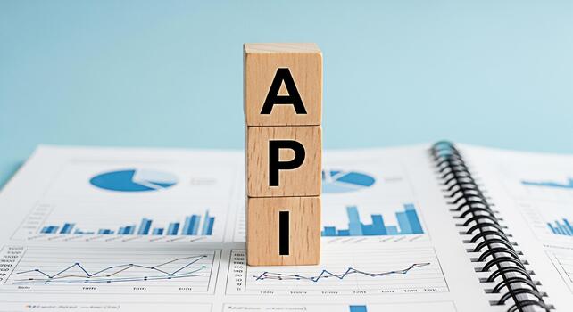Wooden blocks spelling API on top of a financial report in a bright studio setting symbolizing application programming interface and data analysis for business growth and technological advancement photo