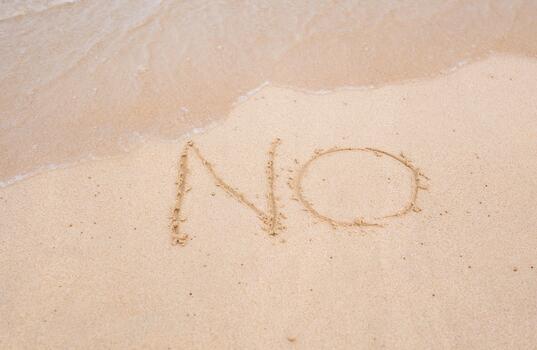 NO sign written in sand on beach texture sunny background. Closeup photo
