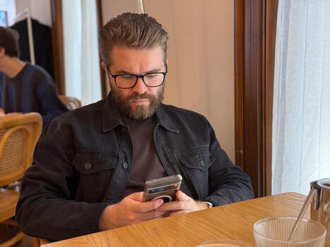 Man sitting by window in cafe using smartphone. Focus, routine and calm atmosphere of modern urban life. photo