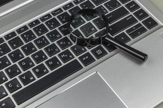 Magnifying glass on a laptop keyboard showing different characters and keys photo