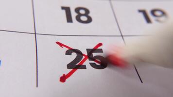 highlighting datum siffra 25 på en kalender, med en djärv röd korsa mark betona ett Viktig påminnelse eller planerad händelse. video