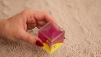 ein Hand hält ein bunt Plastik Rassel Innerhalb ein warm, leise zündete Zimmer. das Rassel produziert ein laut, lebhaft Klang mit jeder Shake, Hinzufügen Freude zu das Atmosphäre video