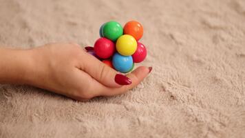 en person skakningar en vibrerande plast boll skallra, skapande en högt och glad ljud. de skallra funktioner flera olika färger och är hölls i en hand mot en mjuk yta video