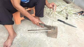 Person using tool for crafting on rough surface with stone and natural elements around in outdoor setting video