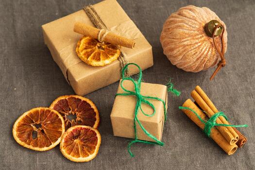 Gift boxes wrapped in plain brown craft paper are adorned with twine and green string, featuring dried orange slices and cinnamon sticks photo