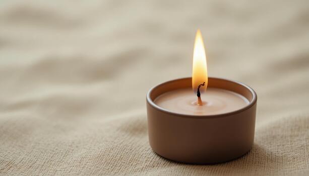 Soft Candlelight Flickers Gently in a Simple Brown Container on a Textured Surface photo