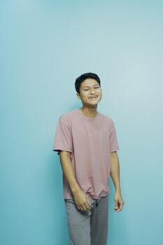 Young asian man smiling and posing in front of a blue background photo