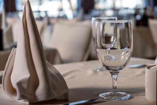 Elegant dining table setting featuring a neatly folded napkin and a crystal glass, showcasing fine dining ambiance with soft lighting and a sophisticated atmosphere photo