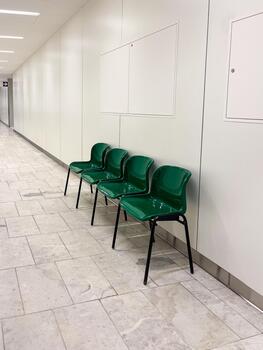 Modern hospital corridor featuring clean, spacious design with green chairs arranged neatly, creating a welcoming atmosphere for patients and visitors in a well-lit environment photo