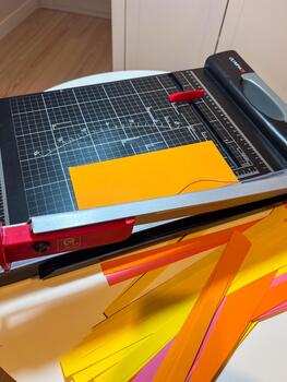 Paper cutting machine with vibrant colored sheets positioned on a cutting table, showcasing the precision tool for crafting and design projects with copy space photo