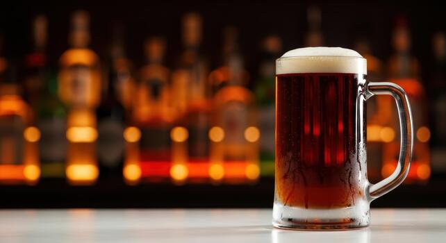 A mug of dark beer with a frothy head sits on a white counter in front of a blurred bar background photo