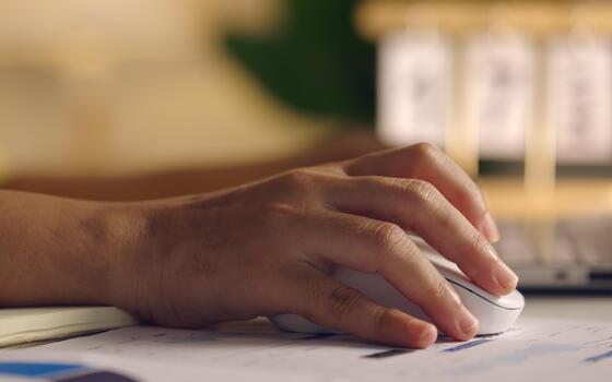 Close up woman hand click on wireless computer mouse working online on laptop computer at home . photo