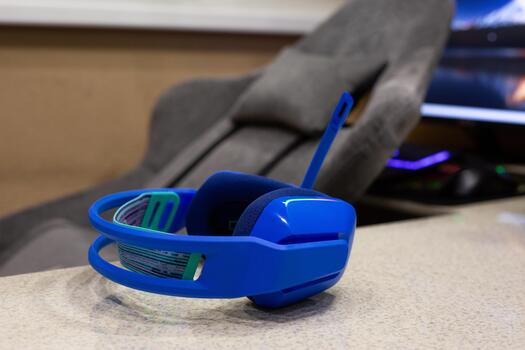 Blue gaming headphones on table with gaming computer in background. Concept photography for gaming at home in a cozy, comfortable setting photo