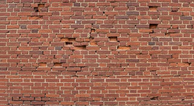 Distressed red brick wall with missing bricks creates a captivating textured background for unique designs, perfect for adding vintage charm photo