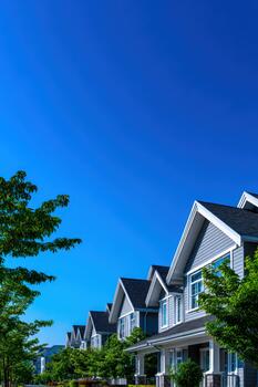 Modern building facade with clear blue sky and trees in the foreground photo