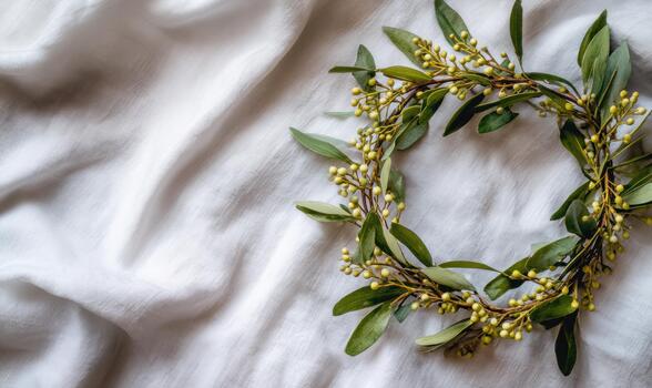 A wreath of green leaves is placed on a white cloth photo