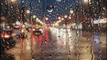 Vertical of rain drops on a window at night. Blurred city lights create a colorful bokeh background. Atmospheric and moody urban scene with a passing car video