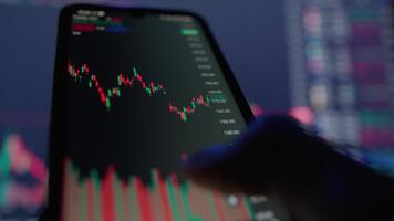 esta imagen muestra un de cerca de un moderno teléfono inteligente mostrando tiempo real valores mercado datos, presentando candelero cartas y vistoso indicadores en un vibrante digital comercio ambiente video