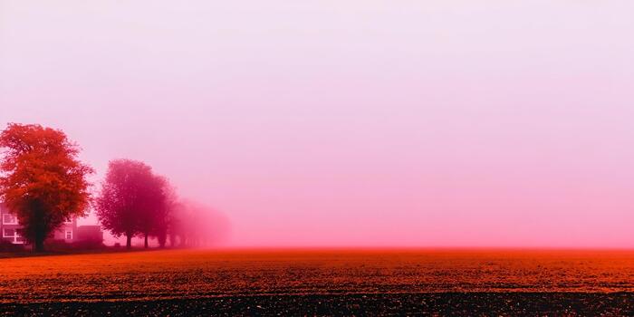 Pink and red fog envelops a field with trees and a house creating a surreal and eerie landscape photo