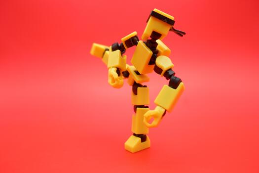 Yellow Dummy Action Figure Performing a Kick Pose on Red Background photo