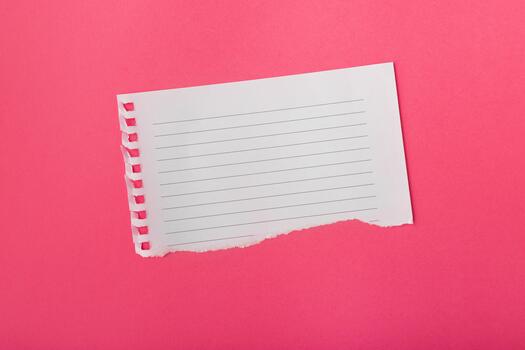 Flat lay white ripped torn sheet of notebook paper on vibrant red surface background photo
