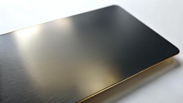 Brushed Metal Card with Reflective Surface, A close up shot of a sleek black rectangular object with a golden edge on a white surface. Mockup Idea. photo