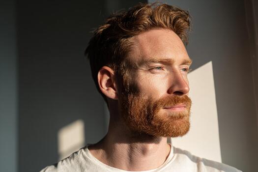 Bearded Redhead Man in Sunlight with Thoughtful Expression photo