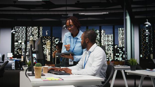 African american team engaged in business planning and report writing, using company data insights to ensure alignment with objectives. Agenda for future projects, after hours. photo