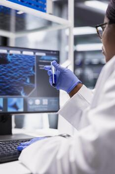 Close up of black expert does laboratory testing with flasks and containers, studying DNA sample with modern equipment. Scientist focused on genetics research and bio science. photo