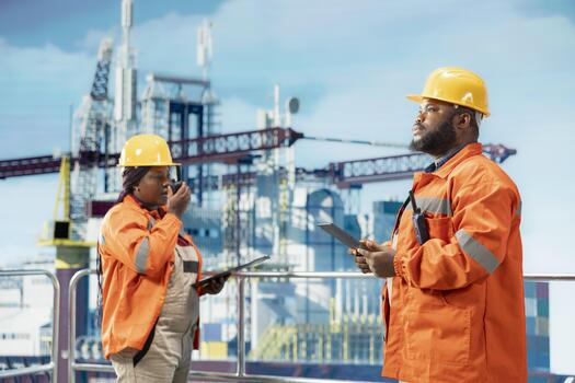 Offshore platform colleagues supervising deck operations with tablets, ensuring compliance with safety protocols. Team of technicians working together doing preventative maintenance on drilling rig photo