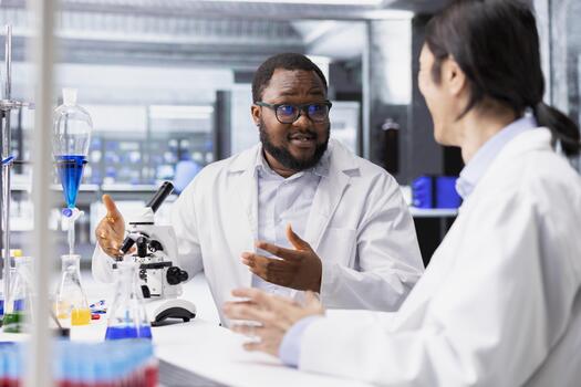 Multiethnic team of microbiologists in laboratory inspecting specimen slide for microscopy study using optical device. Multiracial lab coworkers reviewing cytology slide for clinical testing procedure photo