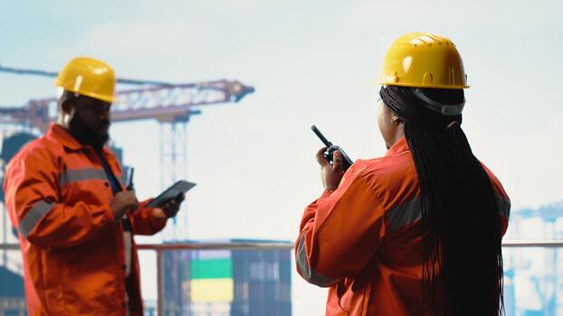 Offshore platform engineer talking in walkie talkie, ensuring compliance with safety protocols. Radio operator in charge of drilling rig communications doing checkup on equipment photo