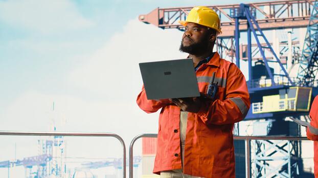 Drilling rig inspector inspecting integrity of offshore platform infrastructure with laptop. Man working on drilling barge using diagnostic tools to detect malfunction in subsea pipelines photo