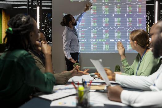 Business advisor reviewing financial analytics indicators during night meeting, conducting a forecast session to discuss training programs. Diverse team enhancing productivity and efficiency. photo